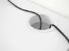 A close-up view of a white desk with a circular grommet and black cables passing through it. Produktbild-Vorschau