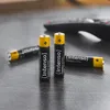 Several batteries are placed on a dark, textured surface, with a blurred remote control in the background. Anteprima dell’immagine prodotto