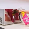 A hand is spraying a microwave with a pink cleaning spray. Produktbild-Vorschau