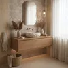 A modern bathroom vanity with a stone-like sink and wooden cabinet, decorated with dried plants. Produktbild-Vorschau
