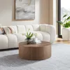 A round coffee table in a living room setting with a sofa and artwork. Produktbild-Vorschau