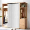 A modern wooden wardrobe with a white pleated curtain covering part of it, and clothing and accessories displayed. Voir les images du produit