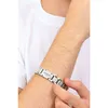 A person's arm wearing a silver Guess bracelet. Podgląd zdjęcia produktu