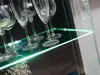 Close-up of champagne flutes on a glass shelf with green LED lighting. Produktbild-Vorschau