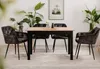 A dining table with four chairs set up in a room with plants and a picture on the wall. Produktbild-Vorschau
