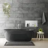 A modern bathroom with a dark gray bathtub, stone tile walls, and a small wooden stool with a plant. Náhled obrázku produktu