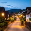 A street lined with houses and streetlights at dusk. Produktbild-Vorschau