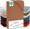 A stack of folded fitted sheets in various colors, with one sheet prominently displayed in the foreground, showing its texture and the elastic edge. Produktbild-Vorschau