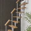 A spiral staircase with wooden steps and silver metal supports against a dark wooden wall and a white wall with some greenery. Produktbild-Vorschau