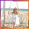 A woman is sitting on a hammock swing on a beach. Produktbild-Vorschau