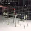 A table and two chairs set up in a modern, minimalist setting with a black tiled wall. Produktbild-Vorschau