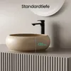 A modern bathroom sink with a black faucet, set against a neutral background with a circular mirror above. Anteprima dell’immagine prodotto
