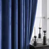 A close-up view of a blue velvet curtain, with decorative candles and books on a table in the background. Anteprima dell’immagine prodotto