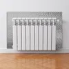 A white radiator with silver insulation behind it, mounted on a white wall above a wooden floor. Náhled obrázku produktu