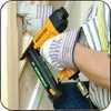 A person wearing work gloves is using a pneumatic nail gun to fasten wooden beams together. Podgląd zdjęcia produktu