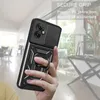 A hand holding a black phone case with a ring holder, in a blurred indoor setting. Produktbild-Vorschau
