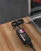 A laptop charger and its cable are plugged into a laptop on a wooden desk. Podgląd zdjęcia produktu