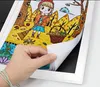 A hand is shown turning the pages of a children's drawing in a white picture frame. Náhľad obrázku produktu