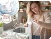 A woman is pouring milk into a breast milk storage bag in a kitchen, with inset images showing breast pump parts being washed and in a dishwasher. Produktbild-Vorschau