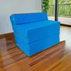 A blue foldable mattress is shown in a room with wooden floors and a large window in the background. Náhled obrázku produktu