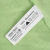 A close-up of a clothing care label on a green fabric. Produktbild-Vorschau