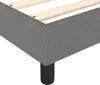 Close-up view of the corner of a dark gray fabric boxspring bed frame with wooden slats and black legs. Produktbild-Vorschau