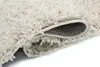 A close-up view of a beige shaggy rug, showing the texture and the underside where it is rolled. Anteprima dell’immagine prodotto