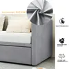 A close-up view of a grey sofa bed with pillows, and a circular inset showing a close-up of the fabric. Produktbild-Vorschau