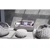 An outdoor furniture set consisting of a sofa, two armchairs, and a coffee table, arranged on a patio with a tiled wall in the background. Produktbild-Vorschau