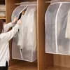 A woman is putting a garment into a transparent garment bag in a closet. Produktbild-Vorschau