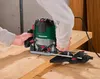 A person is using a PARKSIDE router on a wooden surface. Produktbild-Vorschau