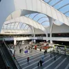 Interior of a modern train station with a large glass roof and people walking around. Voir les images du produit