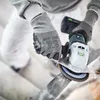 A person wearing safety gloves is using a cordless angle grinder to cut metal, with sparks flying. Produktbild-Vorschau