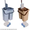Two flat mop buckets with mop heads, one gray and one tan, displayed side-by-side with spare mop heads at the bottom. Náhled obrázku produktu