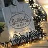 A decorative wooden sign with bakery text and string lights. Produktbild-Vorschau