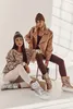 Two women are posing in winter clothing, one sitting on a chair and the other on the floor. Produktbild-Vorschau