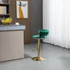 A green velvet bar stool with a gold base is placed next to a kitchen counter with a fruit bowl and a painting on the wall. Voir les images du produit