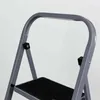 Close-up view of the top part of a gray stepladder with a black platform. Náhled obrázku produktu