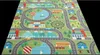 A children's play rug with roads, houses, a Ferris wheel, and a pond. Produktbild-Vorschau