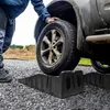 A person is using black plastic ramps to lift a car tire. Podgląd zdjęcia produktu
