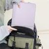 A person is putting a violet laptop sleeve into a backpack. Produktbild-Vorschau