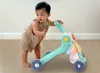 A baby is using a green walker with a colorful activity panel. Podgląd zdjęcia produktu