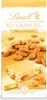 A bar of Lindt Les Grandes 32% Mandeln white chocolate with almonds scattered around it. Voir les images du produit