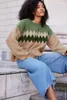 A woman wearing a knitted sweater and jeans sits on stone steps. Produktbild-Vorschau