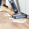 A person is using a BISSELL Crosswave vacuum cleaner to clean up a spill on a wooden floor. Voir les images du produit