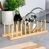 A bamboo dish rack holding two pot lids on a countertop. Produktbild-Vorschau