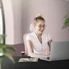 A woman is working on a laptop at a desk in a modern office setting. Produktbild-Vorschau