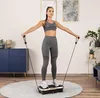 A woman is exercising on a vibration plate in a living room. Náhľad obrázku produktu