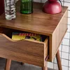 A close-up of a wooden nightstand with an open drawer revealing a book. Produktbild-Vorschau