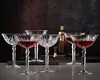 A set of crystal cocktail glasses filled with red liquid, arranged on a countertop with a bar shaker in the background. Produktbild-Vorschau